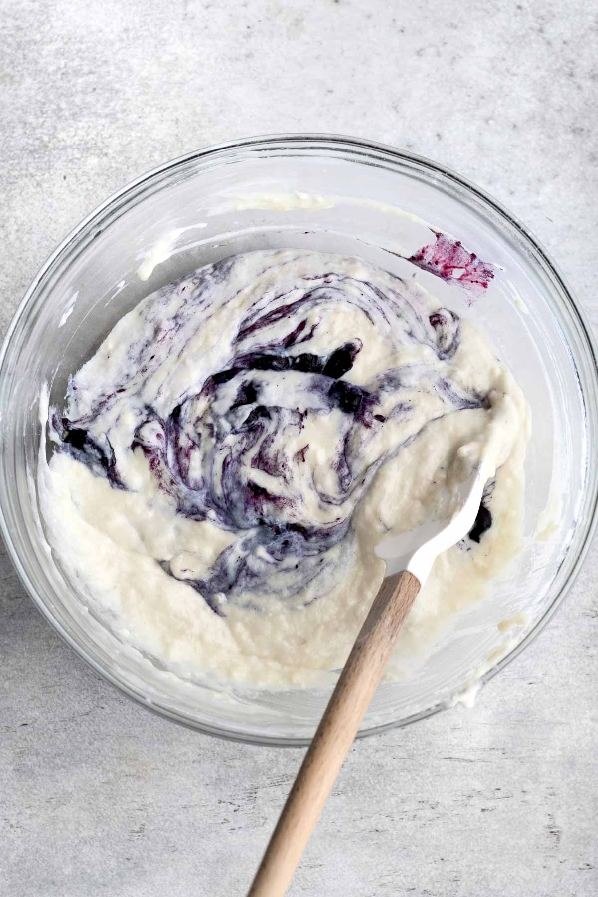 Blueberries streak in the white batter.