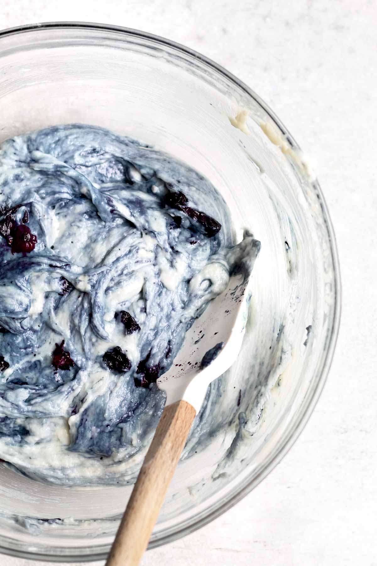 Mixing more blueberries into the batter.