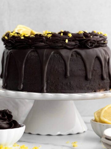 Chocolate Lemon Cake on a stand with star sprinkles and slices of lemon.