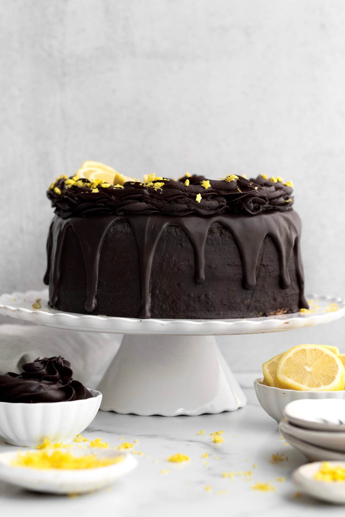 Chocolate Lemon Cake on a stand with star sprinkles and slices of lemon.