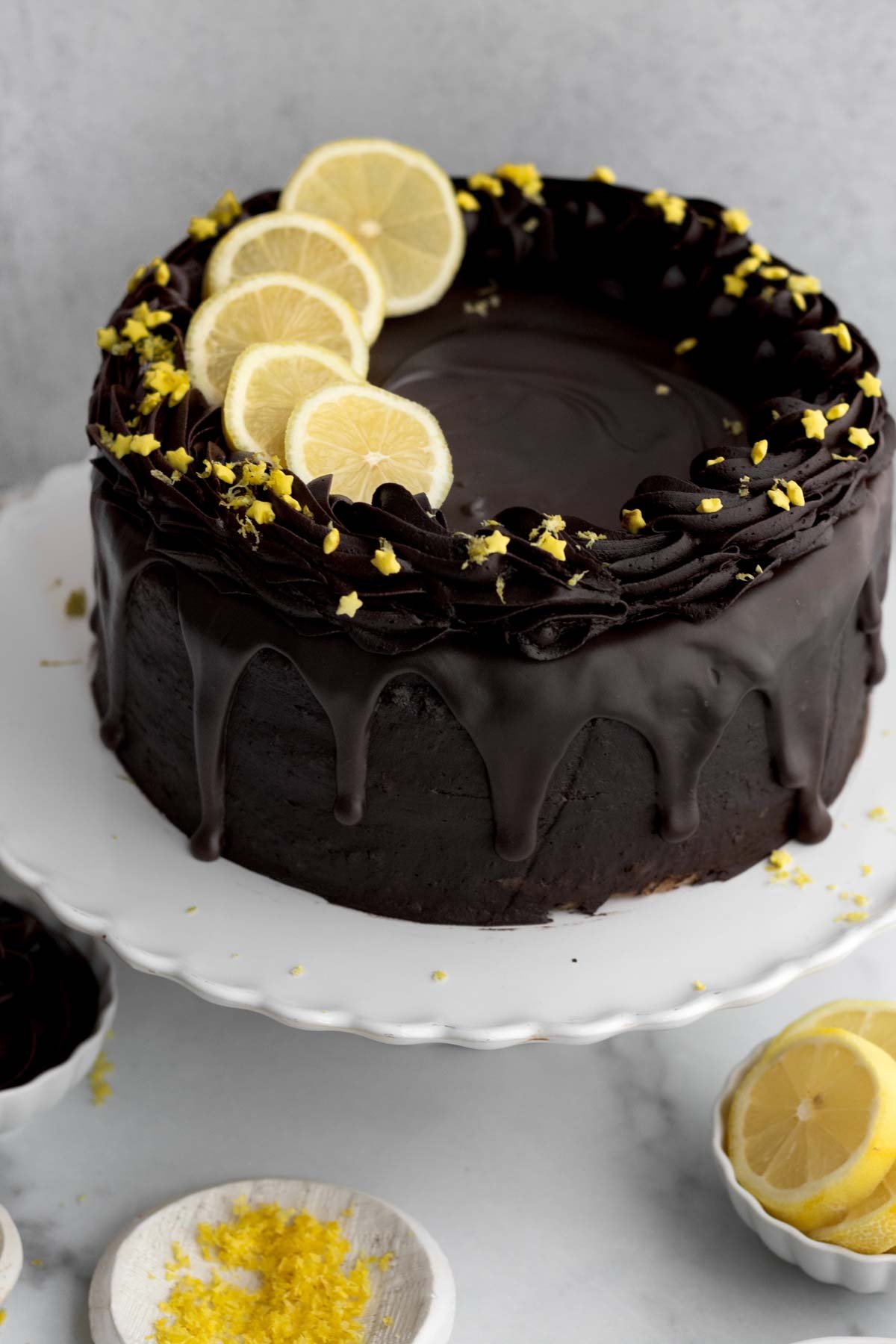 Cake dripping with chocolate and topped with lemons, zest and sprinkles.