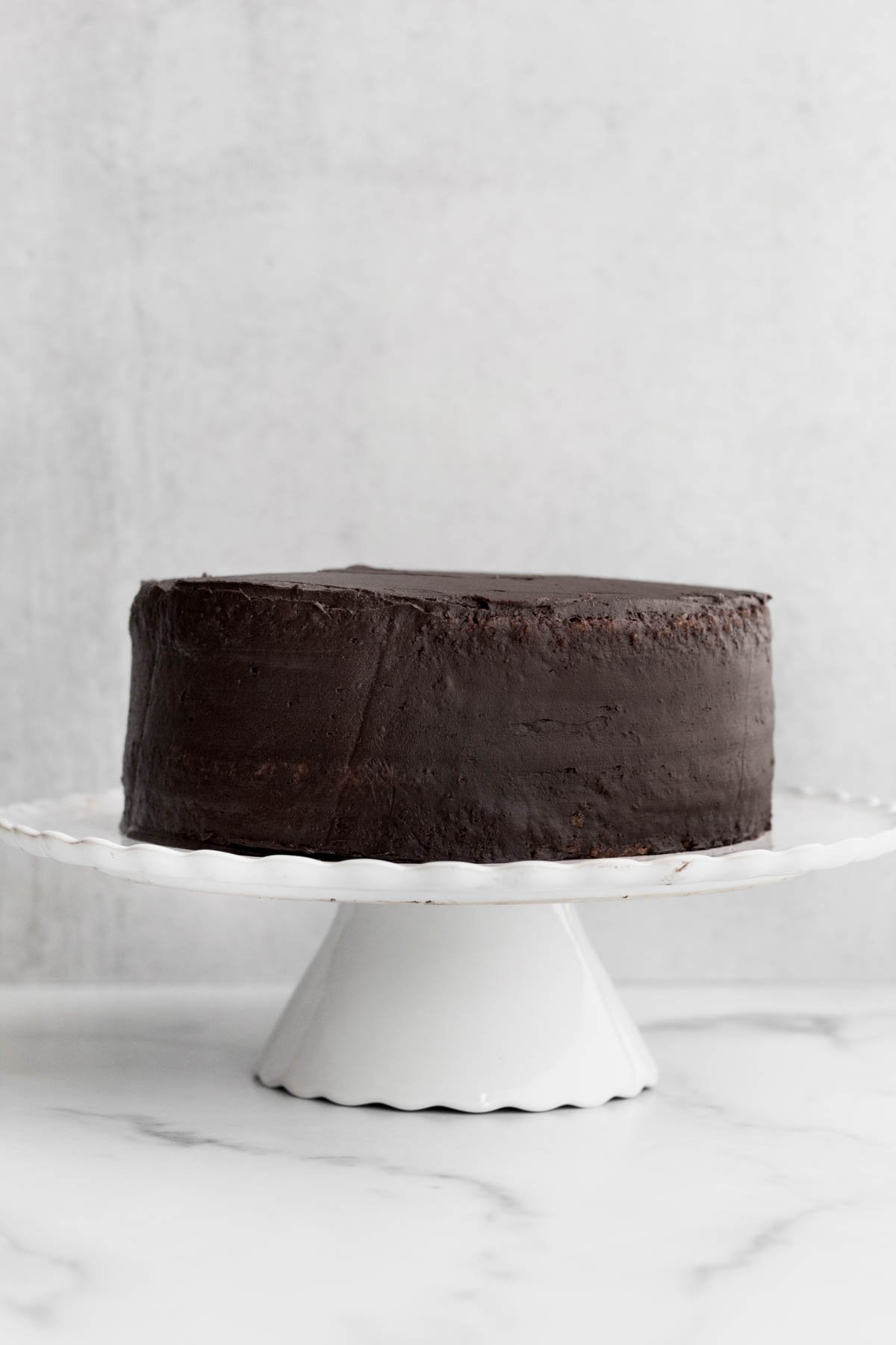 Chocolate frosted cake on a cake stand.