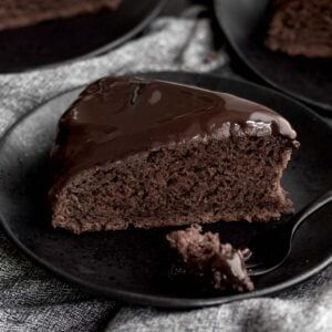 A slice of chocolate glazed cake with a fork.