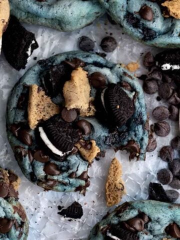 A blue cookie with chocolate chip and sandwich cookies on top.