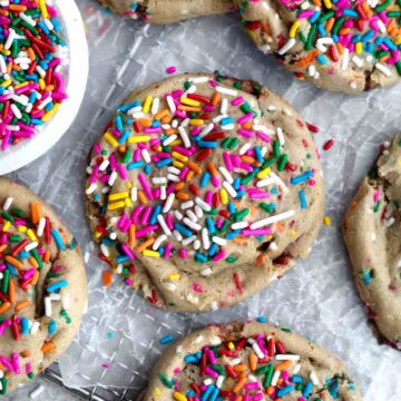 Colorful bright rainbow sprinkles arranged sporadically atop gluten free Funfetti Cookies.