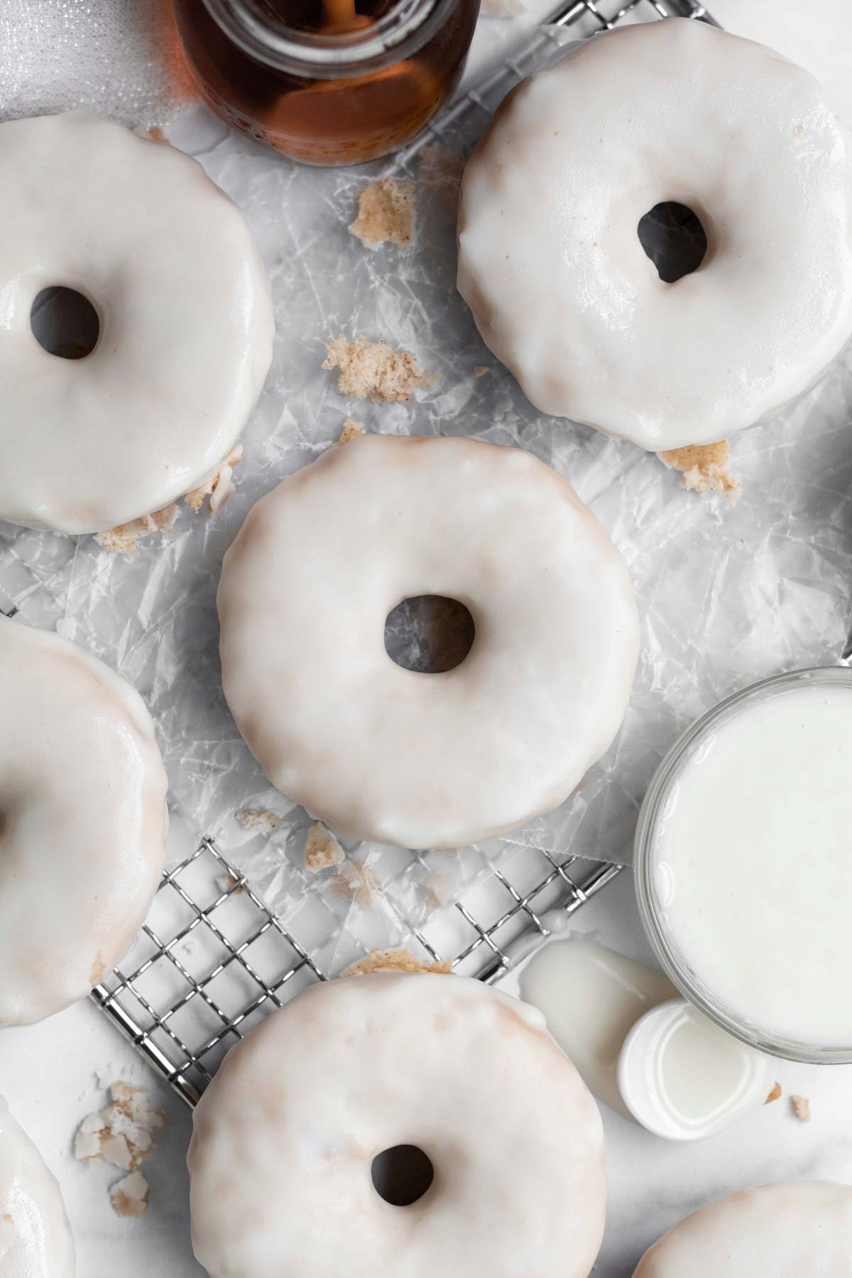 Looking down at glazed donuts on wax paper.