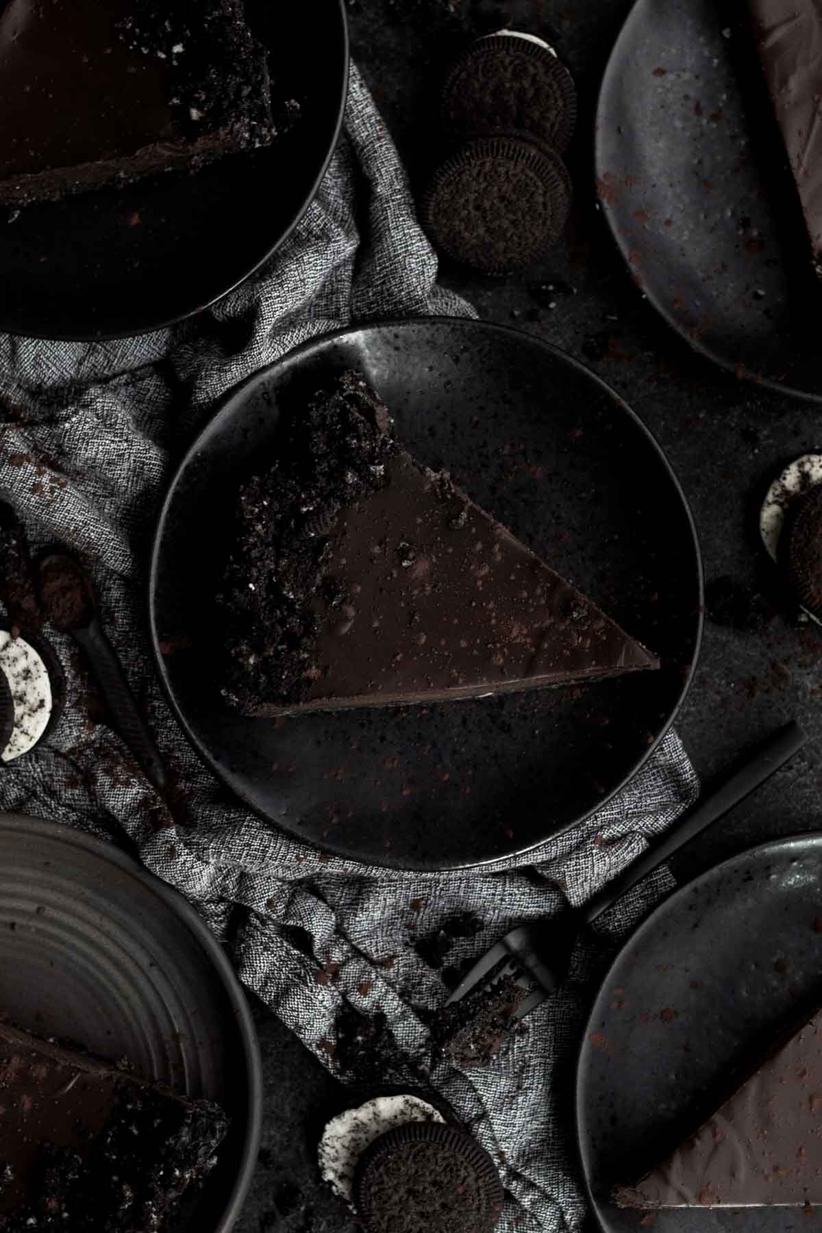 A slice of chocolatey tart on a black plate.