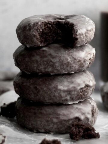 A stack of four glazed chocolate donuts.