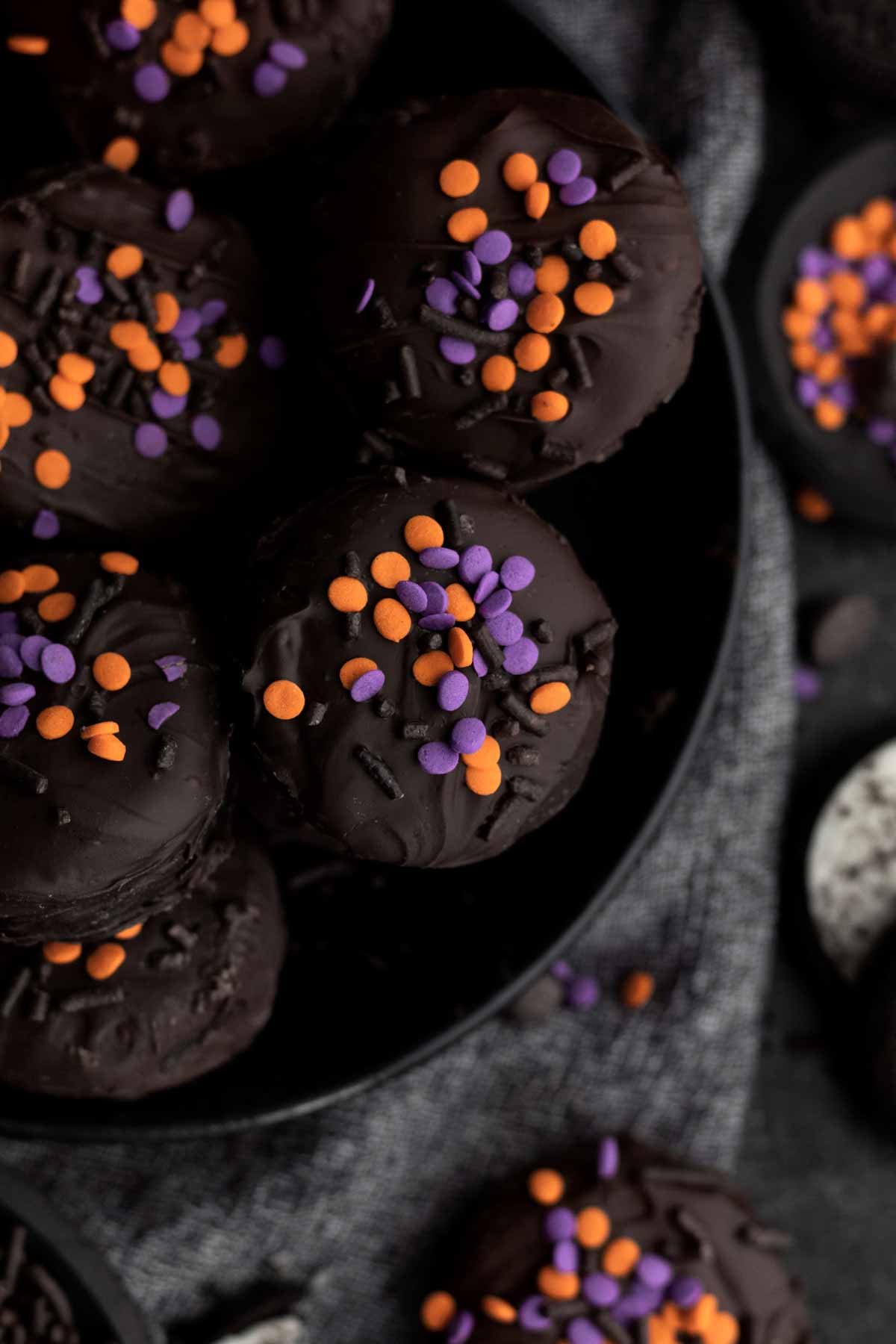 A plate of chocolate covered Oreos with sprinkles.