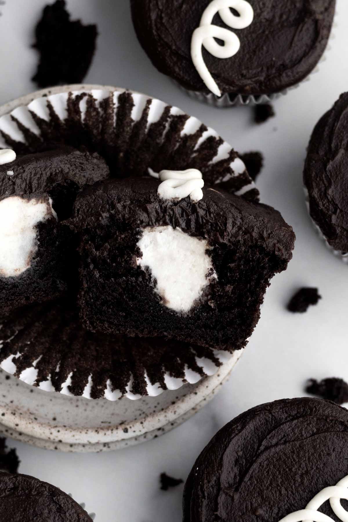 A chocolate cupcake sliced in half with a vanilla frosting core.