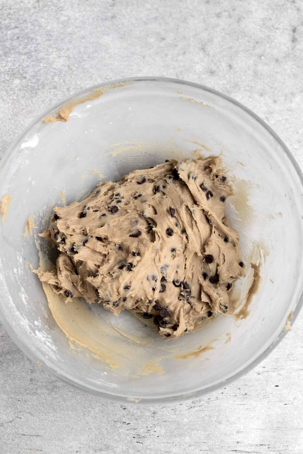 A glass bowl with chocolate chip cookie dough batter.