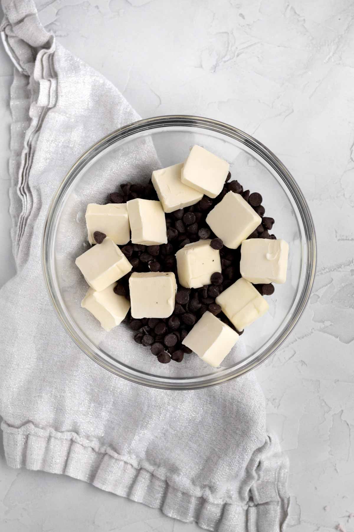 Slices of butter and chocolate chips in a glass bowl.
