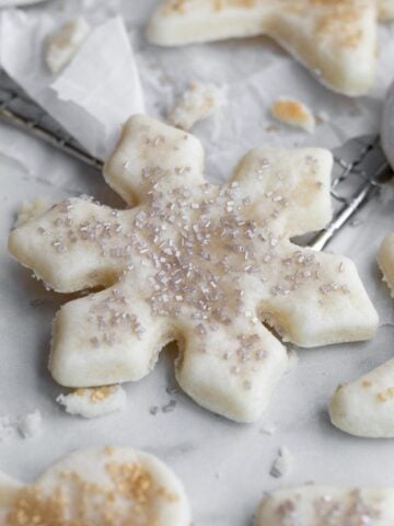 A snowflake shaped sugar cookie with silver sugar sprinkles.
