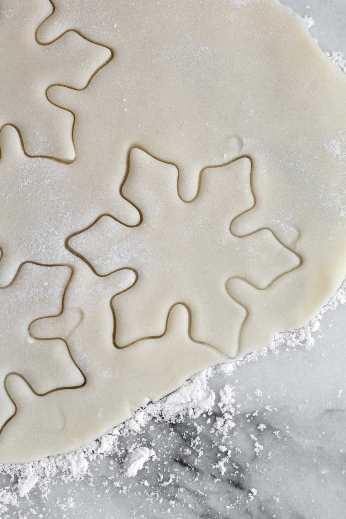 Snowflake shaped cookie cuts on the dough.