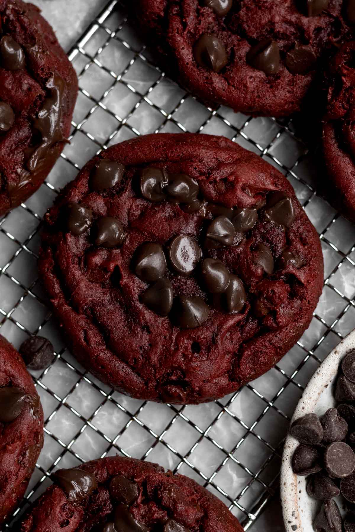 Melted chocolate chips dot the red landscape of the warm and soft cookie.
