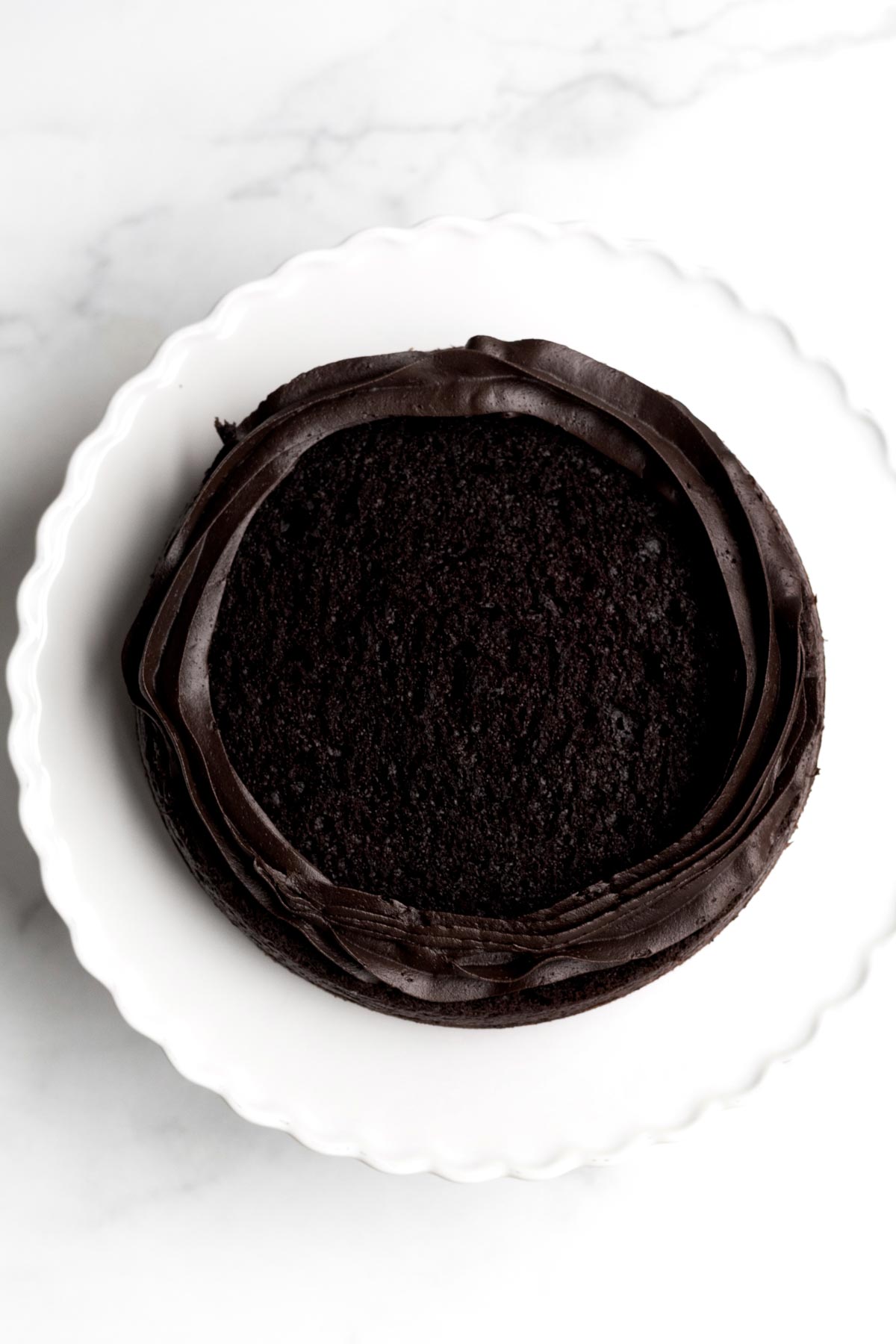 A piped ring of chocolate frosting around the top of the chocolate cake.
