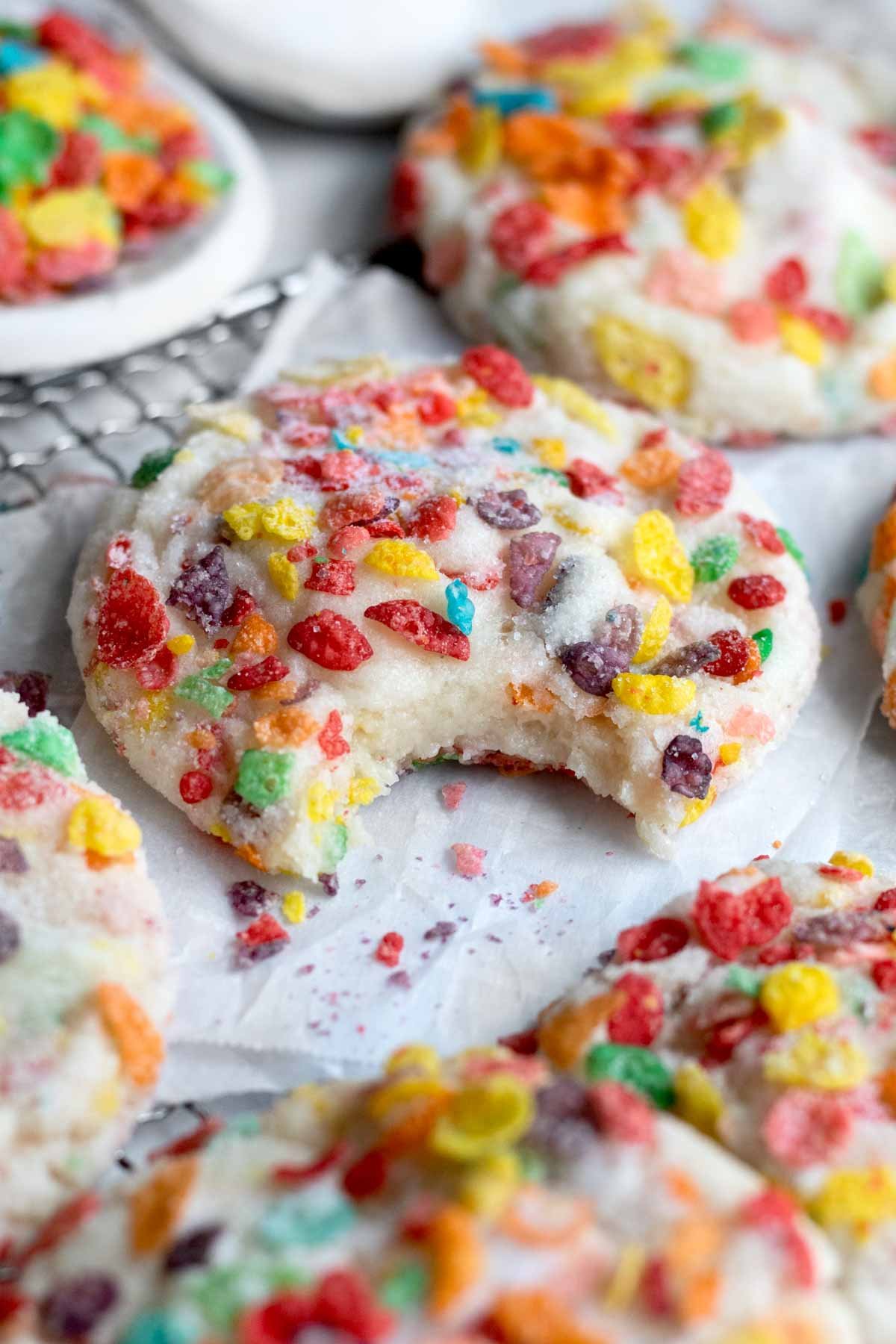 A bitten cookie with fruity pebbles and granulated sugar.