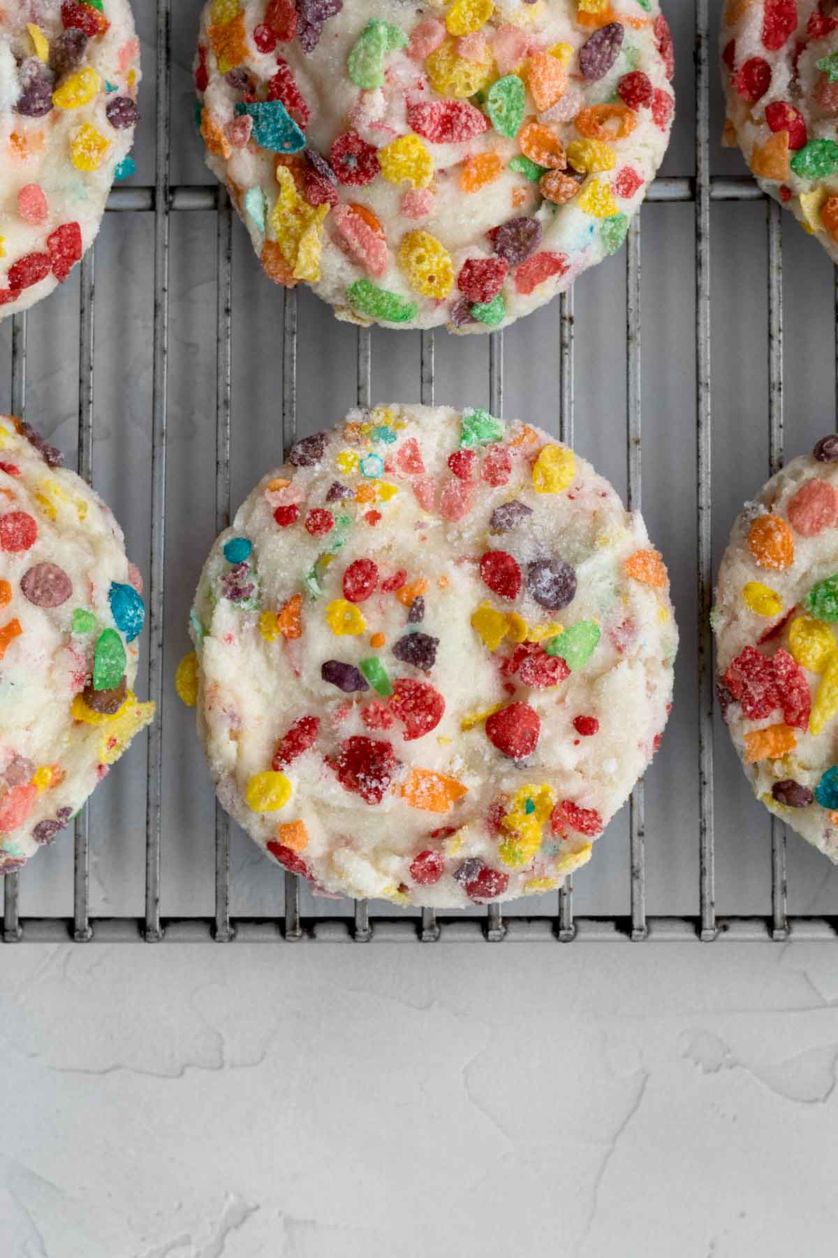 Round warm Fruity Pebbles Cookies on a baking rack.