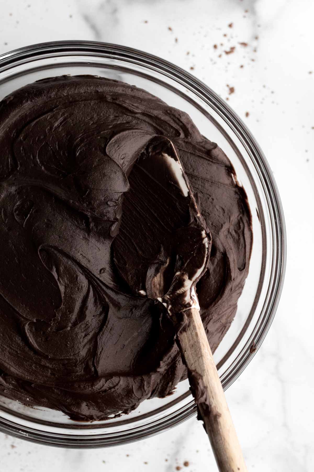 Rich chocolate frosting mixed with a spatula.