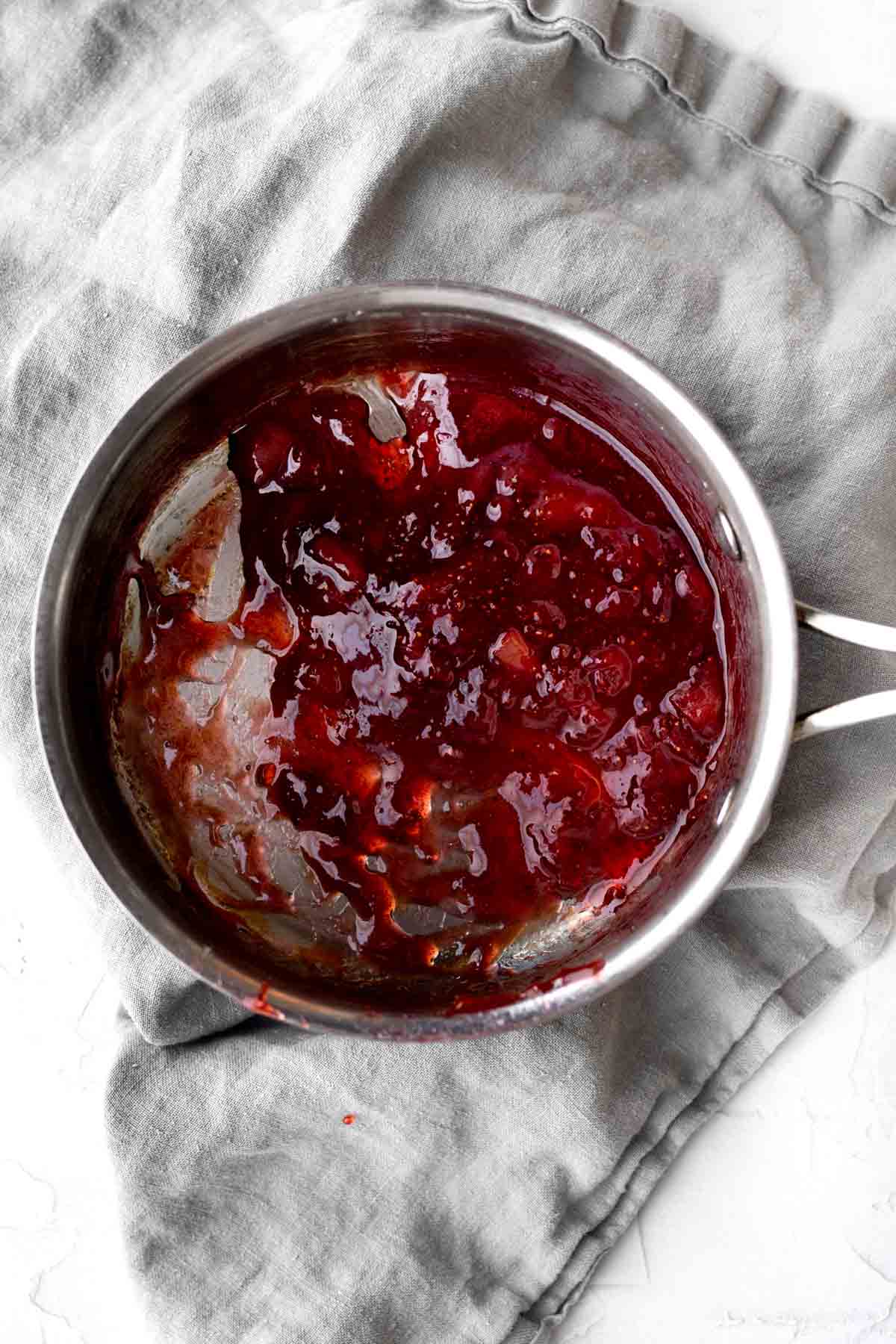 Hot liquid strawberry sauce in a saucepan.