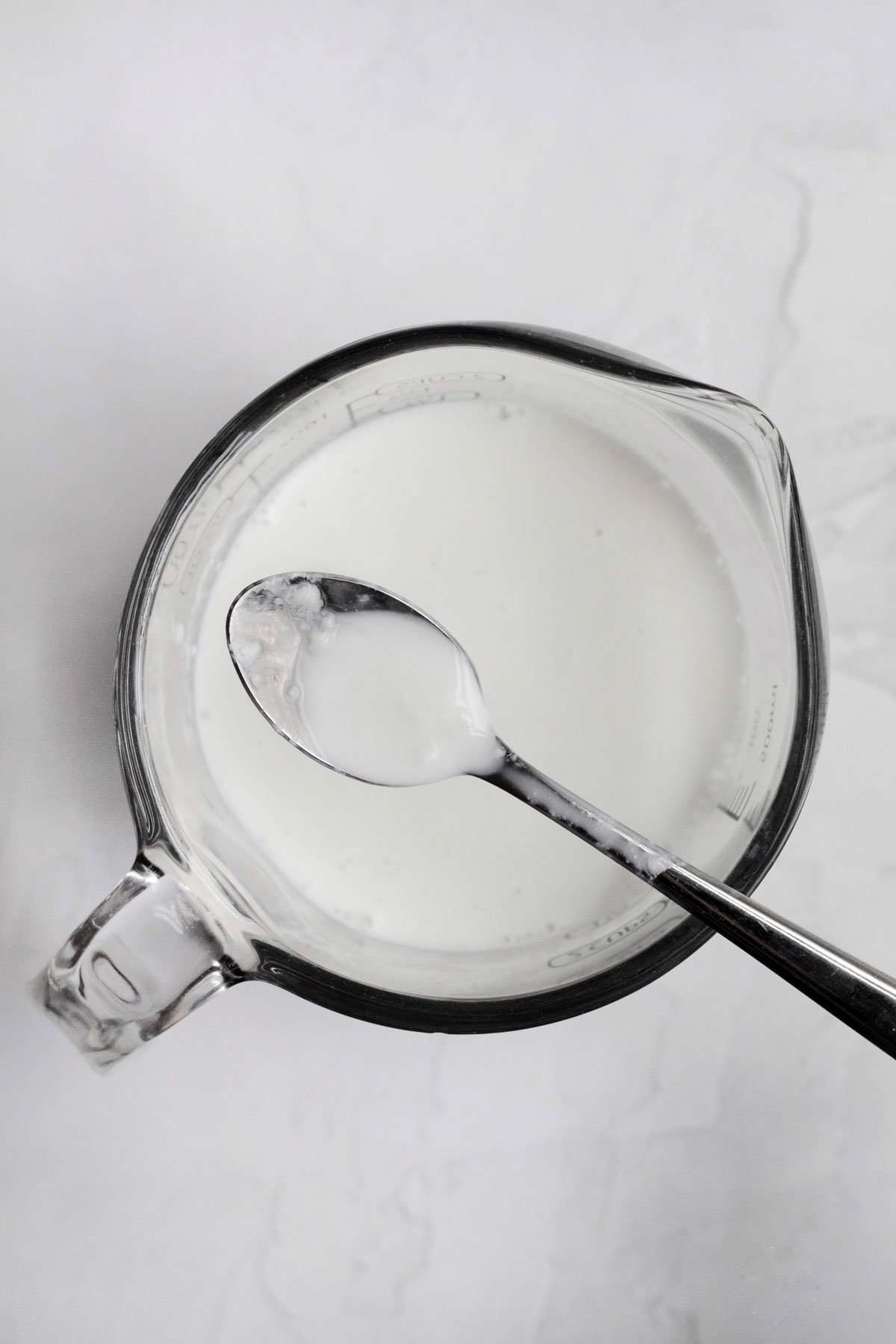 Homemade buttermilk in a measuring cup with a spoon.