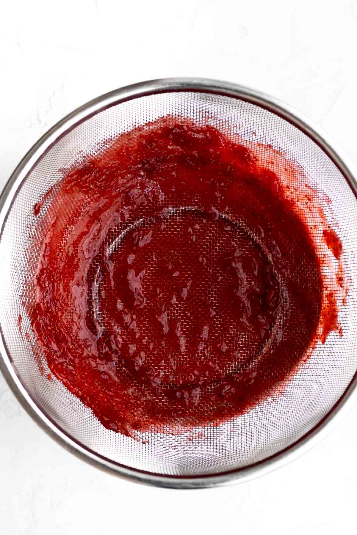 A strainer stained red from the strawberry puree.