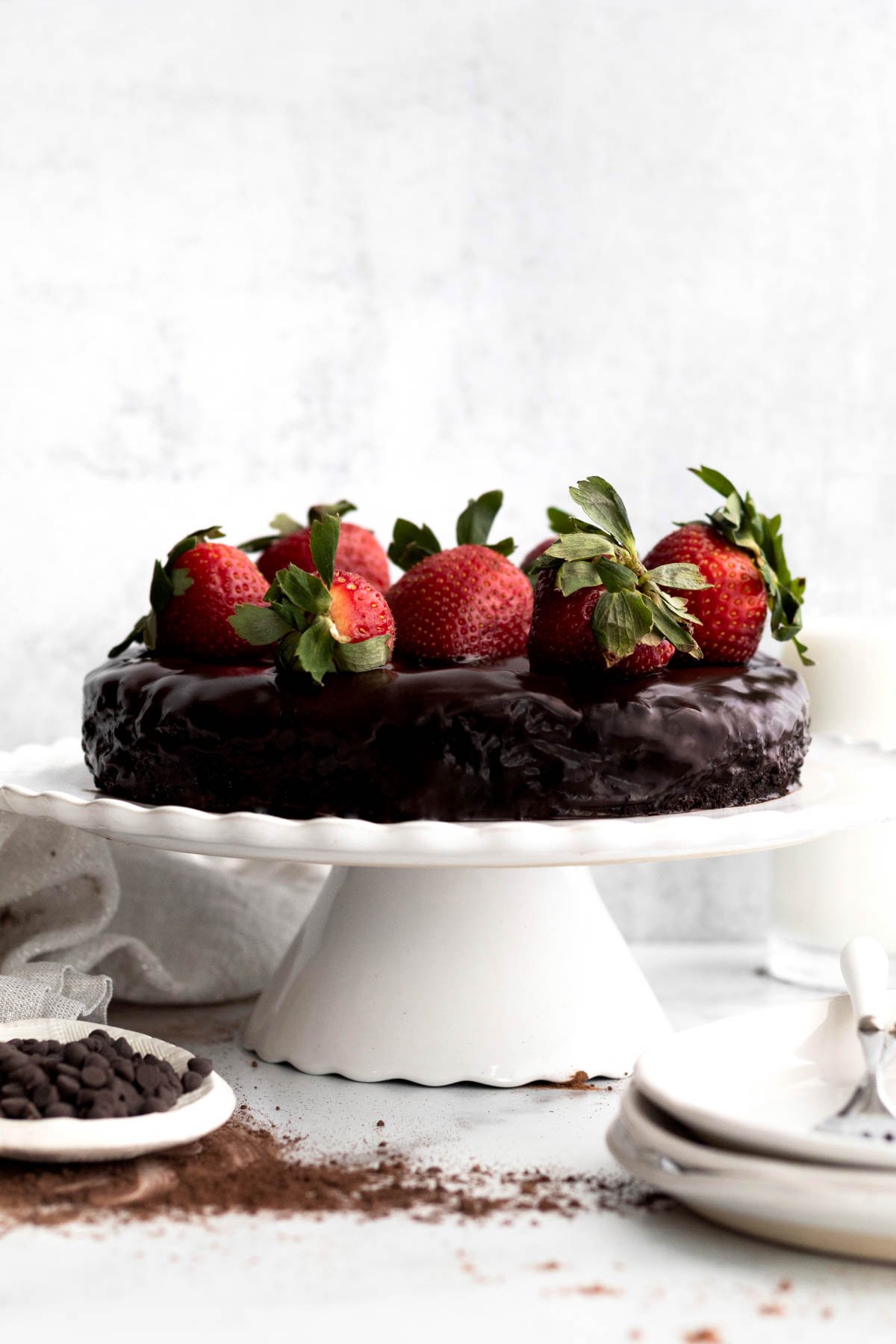 Rich delicious vegan flourless cake on a cake stand with strawberries.