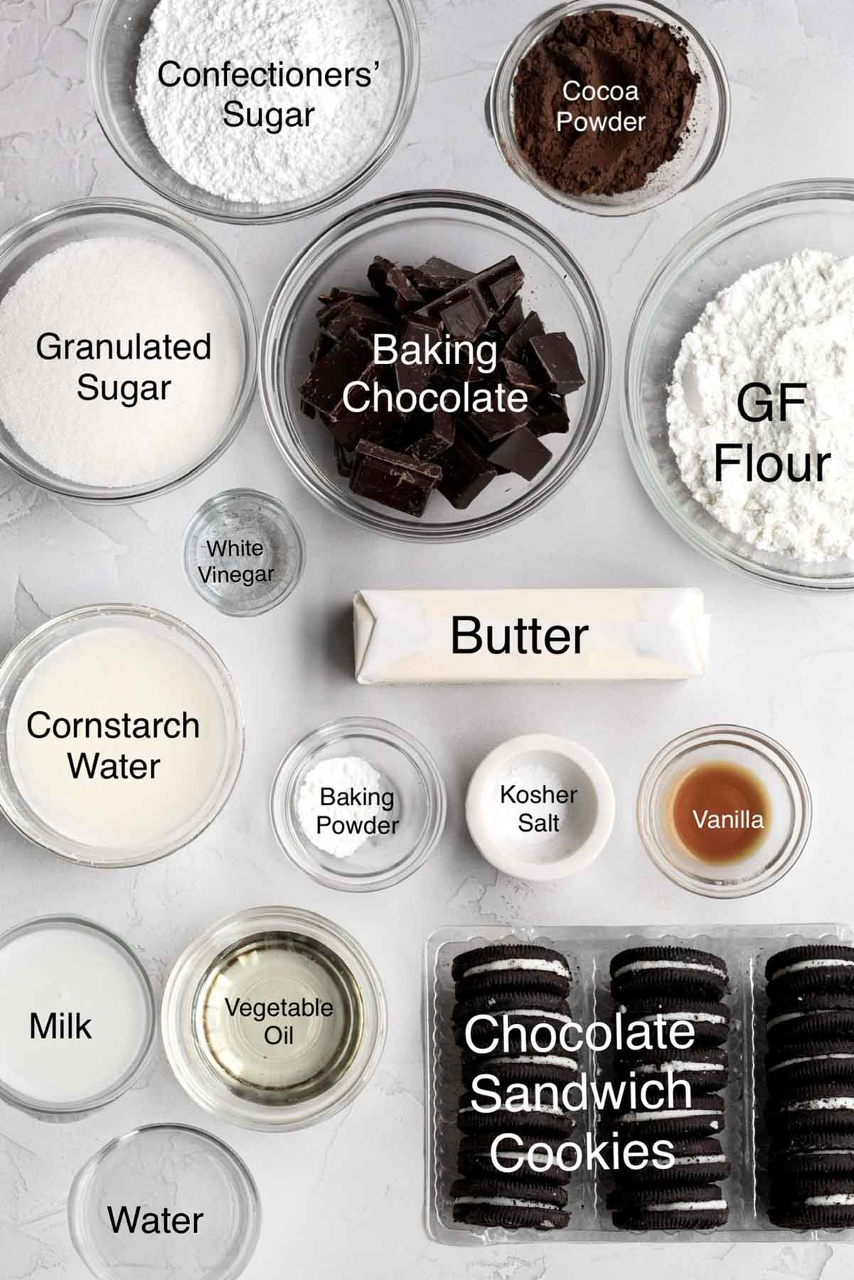 Confectioners' sugar, cocoa powder, granulated sugar, baking chocolate, gluten free flour, white vinegar, butter, cornstarch water, baking powder, kosher salt, vanilla, milk, vegetable oil, water, chocolate sandwich cookies in separate containers.