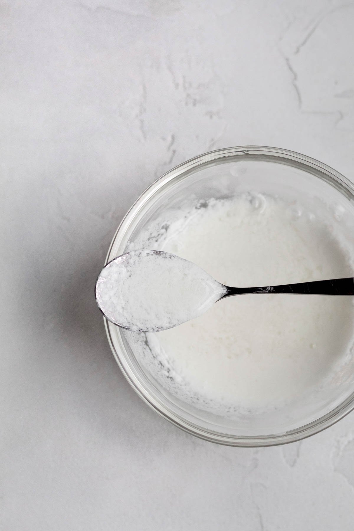 Homemade buttermilk in a measuring cup with a spoon.