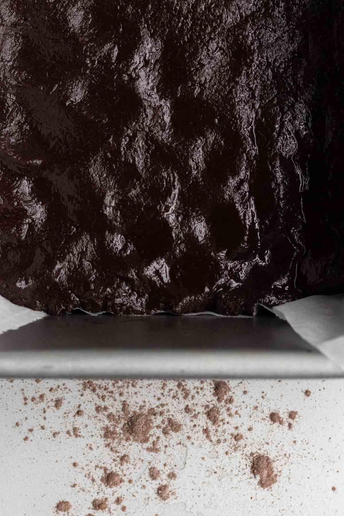 Filling a pan with overhanging parchment paper with the batter.
