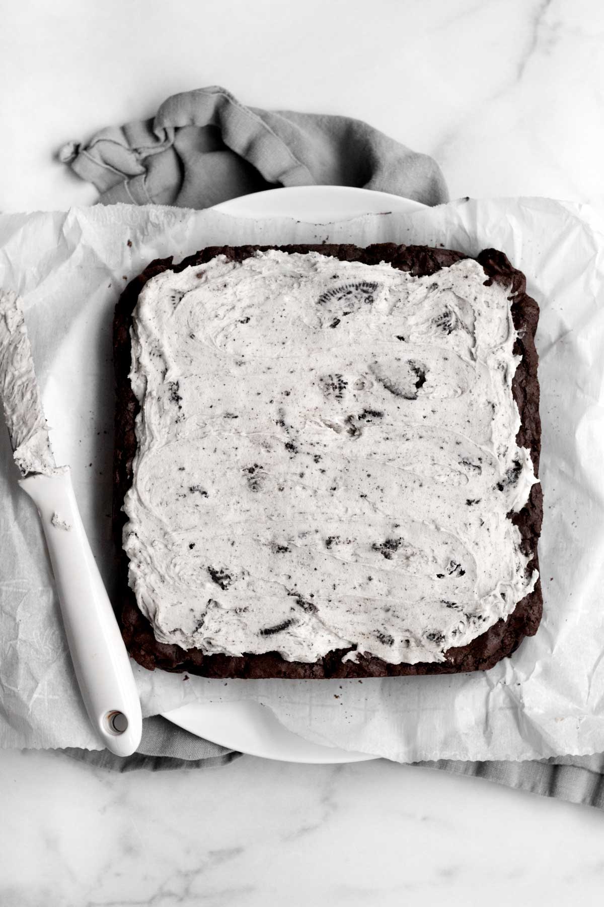 The frosting is smoothed evenly across the brownie.