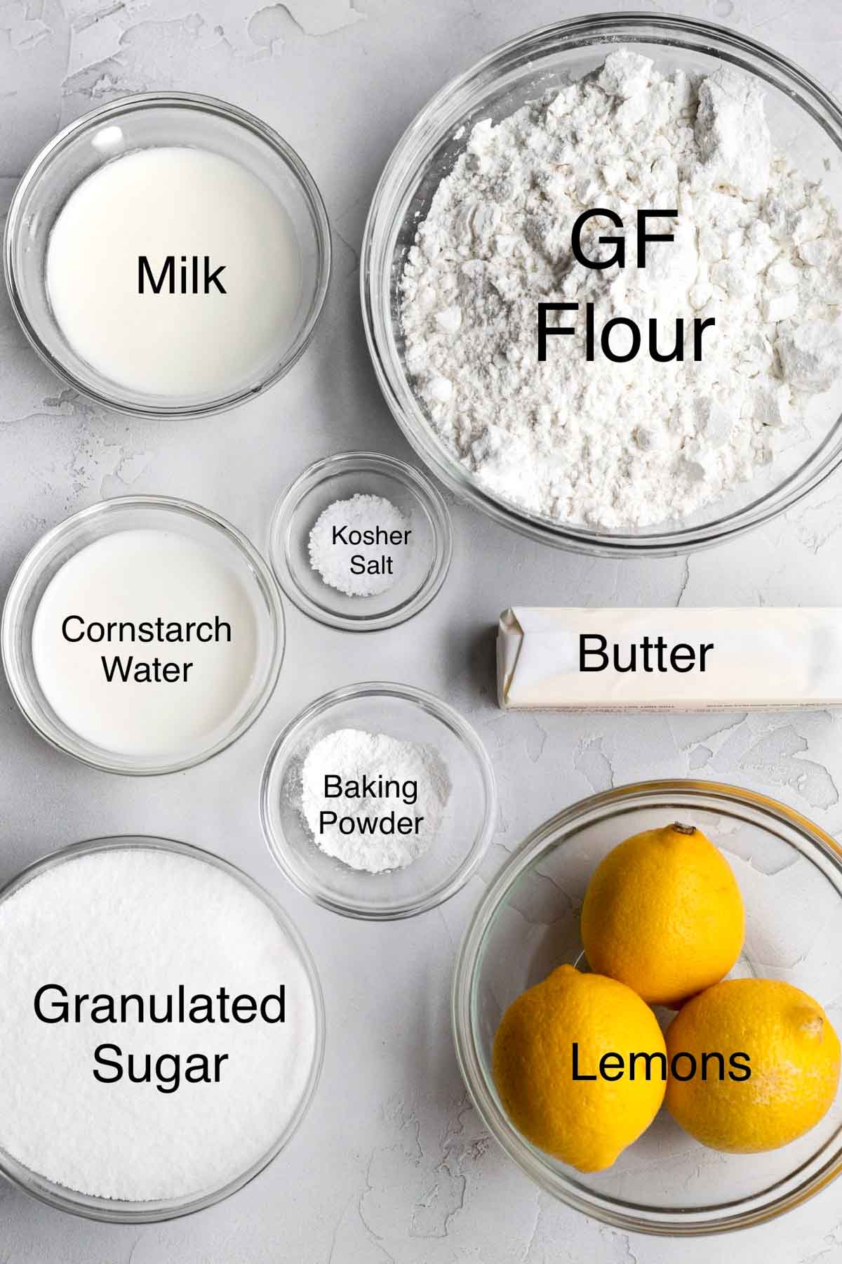 Milk, Gluten free flour, cornstarch water, kosher salt, butter, baking powder, granulated sugar and lemons in separate containers.