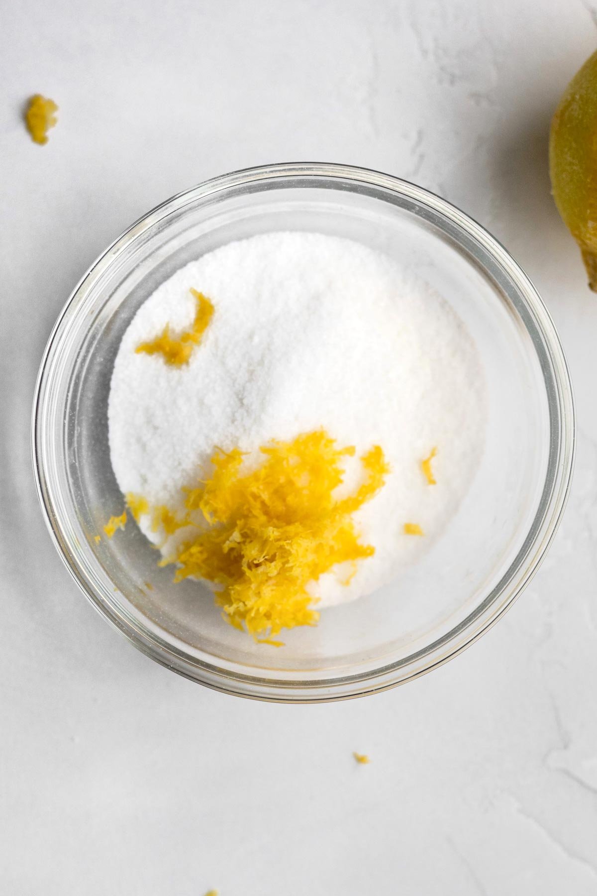 Lemon zest in a bowl of granulated sugar.