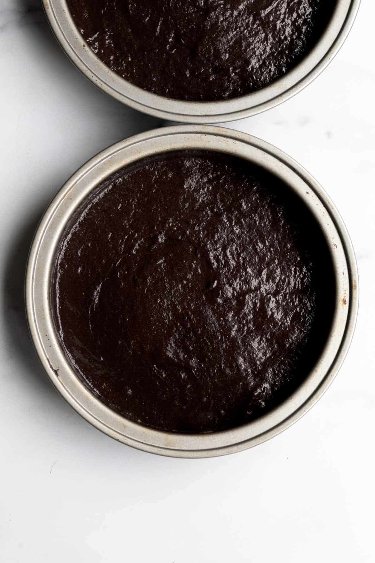 Rich chocolate cake batter in cake pans.