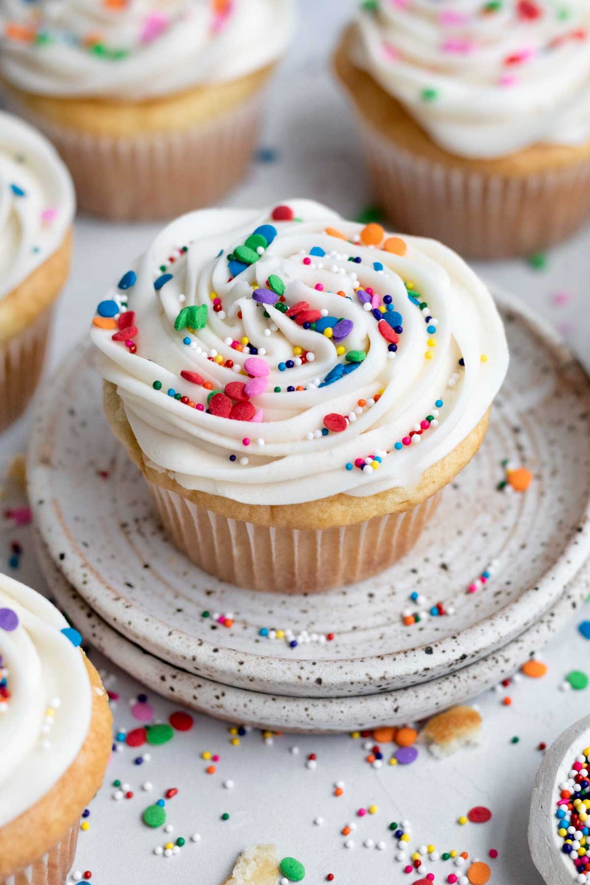 Rainbow sprinkles fall in an eye-catching design on the swirl of the Gluten Free Vanilla Cupcake.