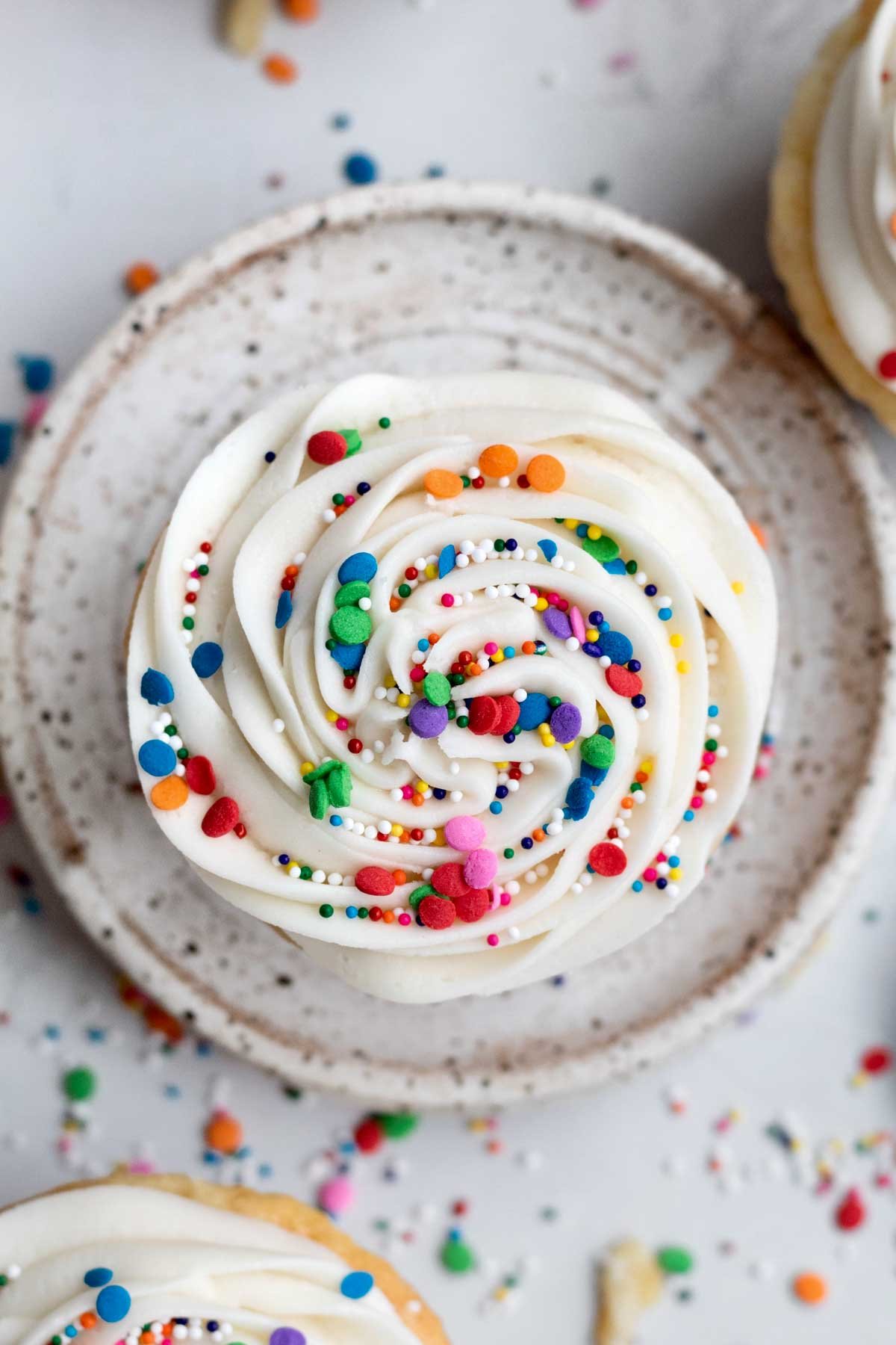 Swirl of the cupcake is a perfectly piped peak of creamy, vanilla frosting with rainbow sprinkles.