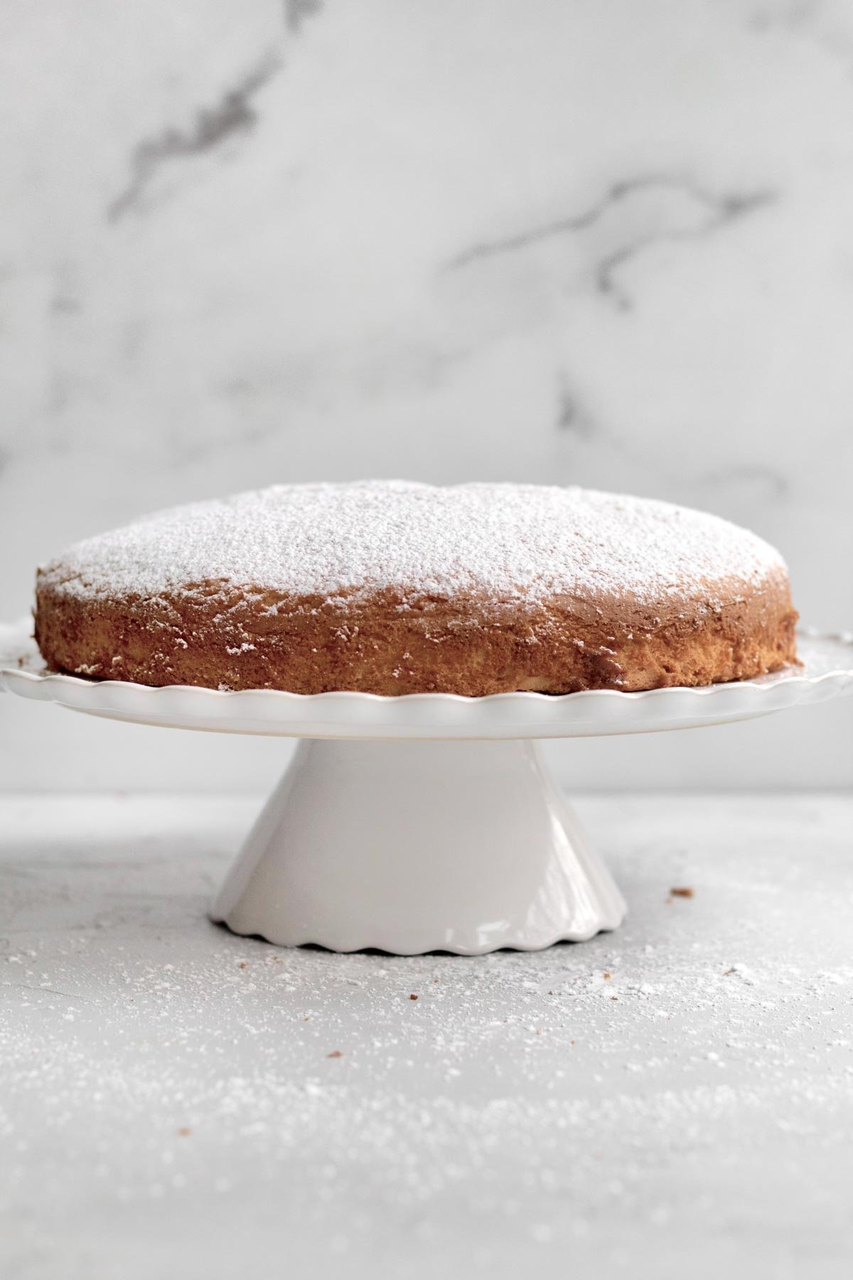 Lightly dusted with confectioners' sugar, this Irish Tea Cake sits on a cake stand.