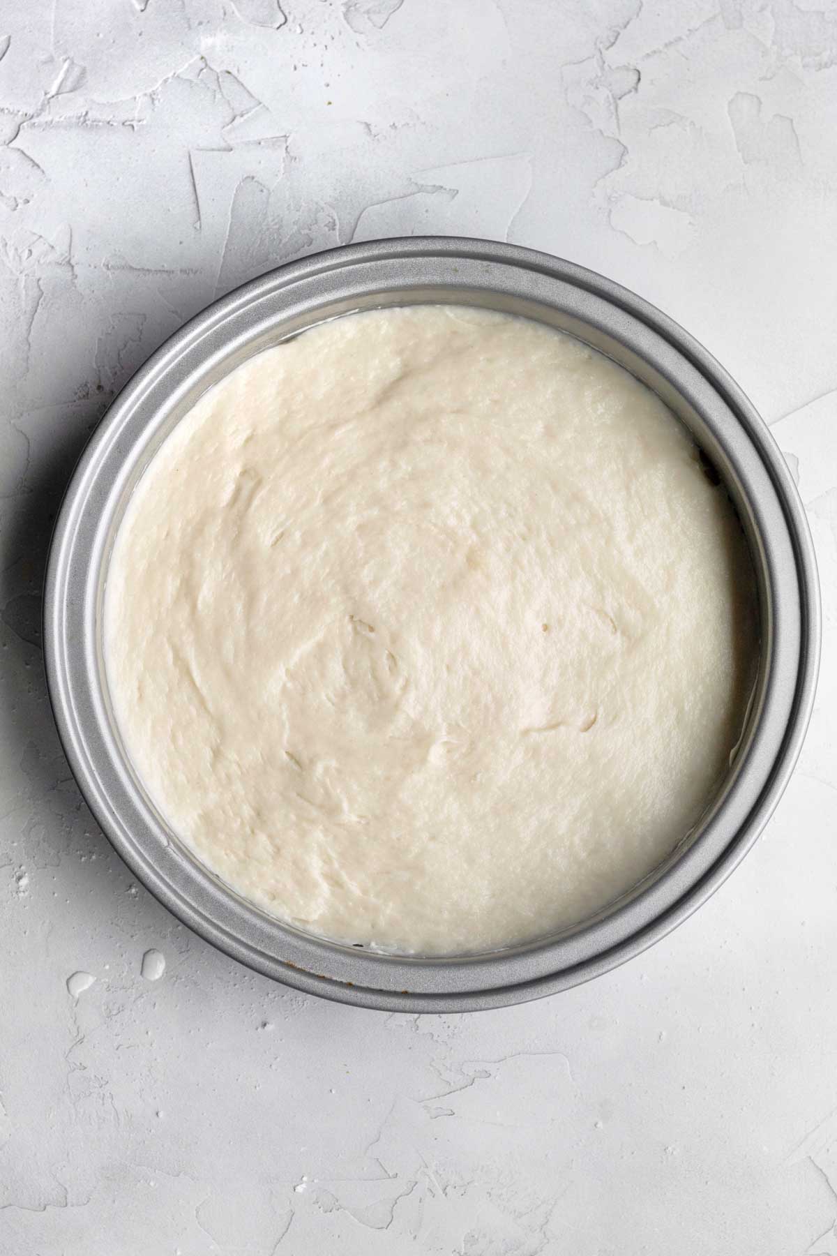 Filling a silver cake pan with the batter.