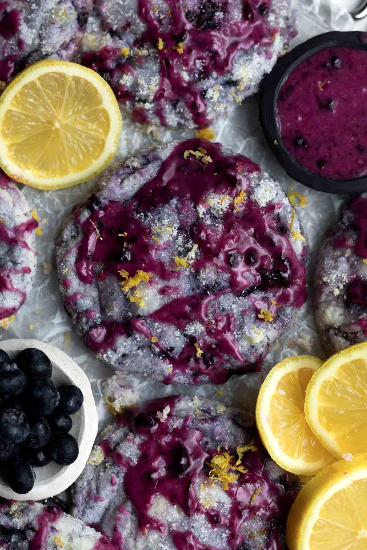 Vibrant purple Lemon Blueberry Cookies covered in sugar and lemon zest drizzled in delicious blueberry glaze.