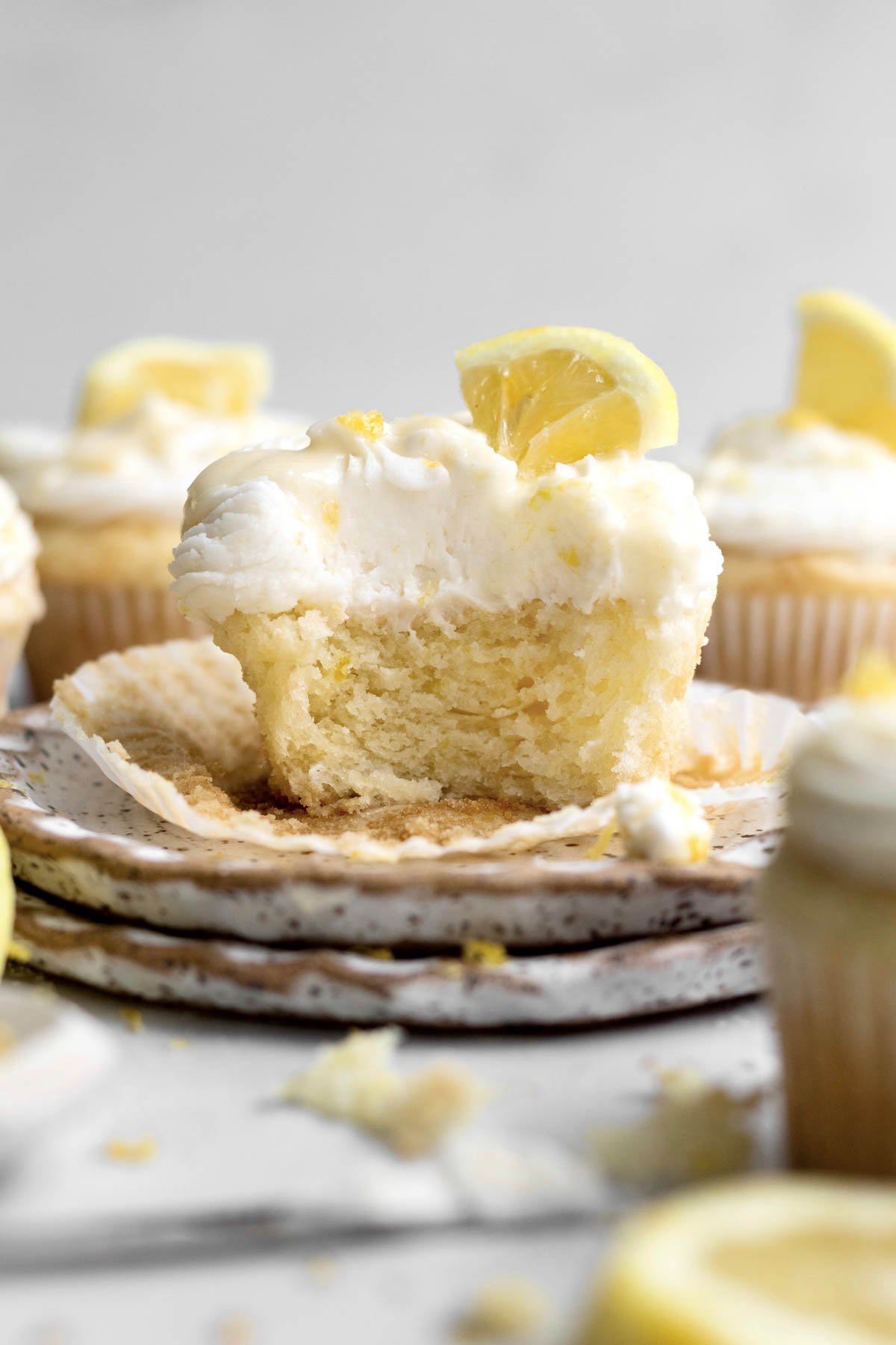 A lemon drizzle cupcake with a bite taken reveals its soft lemony insides.