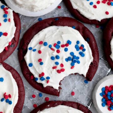 A bite taken from vanilla frosting and red velvet base of this 4th of July Cookie.
