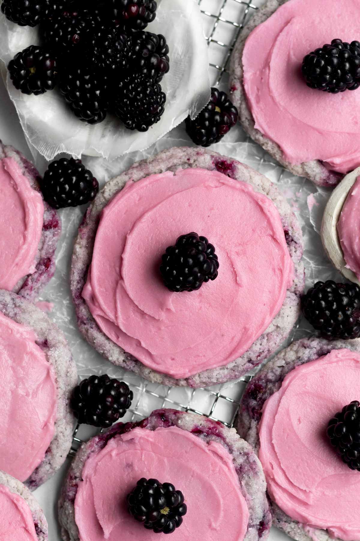 Sweet, soft and tart Blackberry Cookies topped with creamy pink blackberry frosting and a singular blackberry.