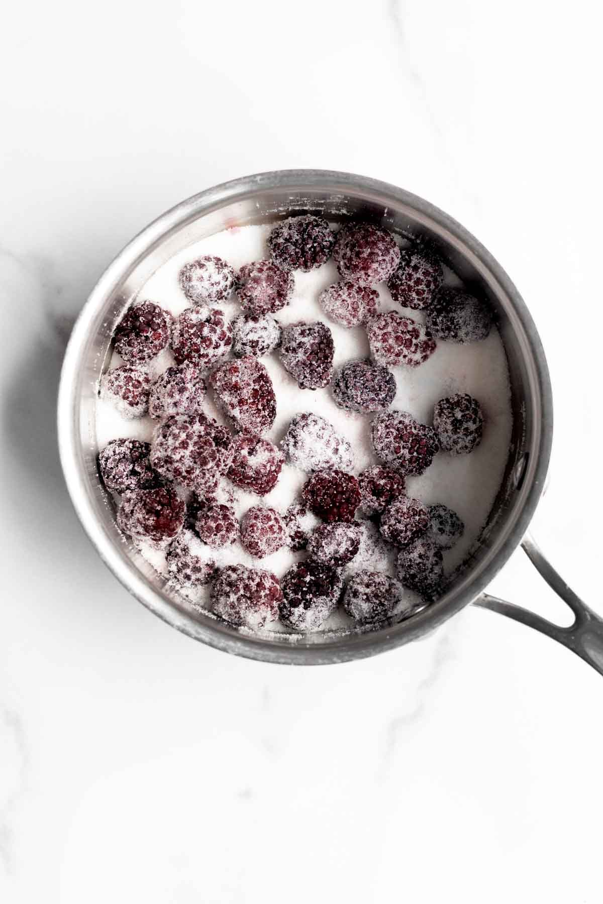 Frozen blackberries and granulated sugar in a saucepan.
