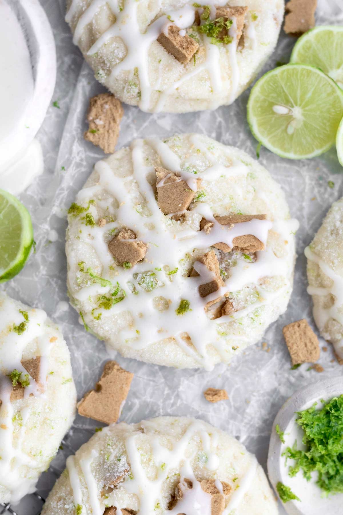 Scrumptious sugar coated Key Lime Cookies adorned with graham cracker shards and sweet cream cheese glaze.