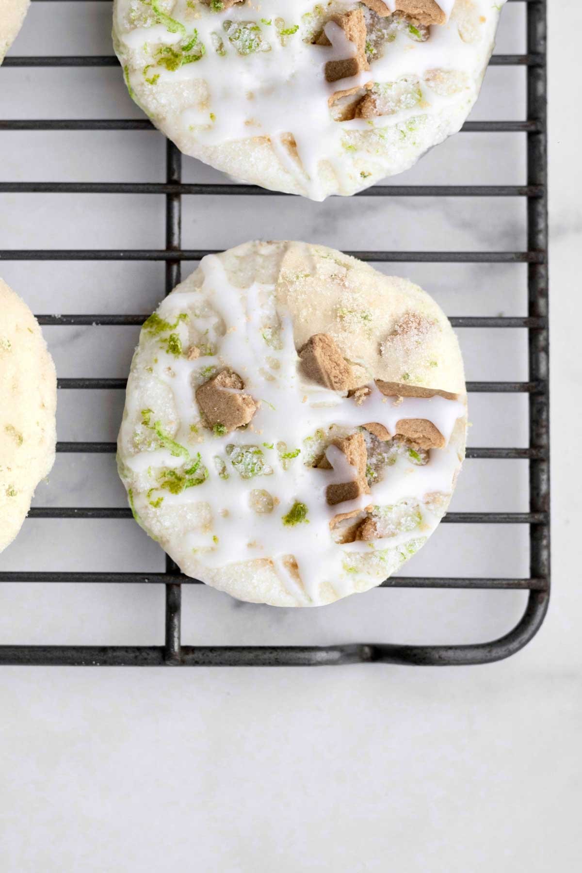 Key Lime Cookies with fresh cream cheese drizzle on a cooling rack.