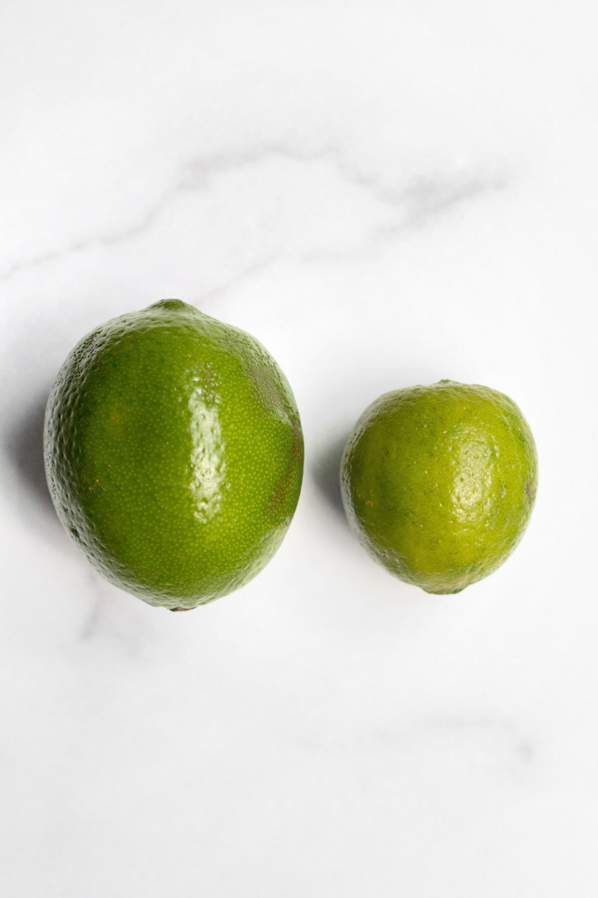 A regular lime on the left is four times as big as the key lime on the right.