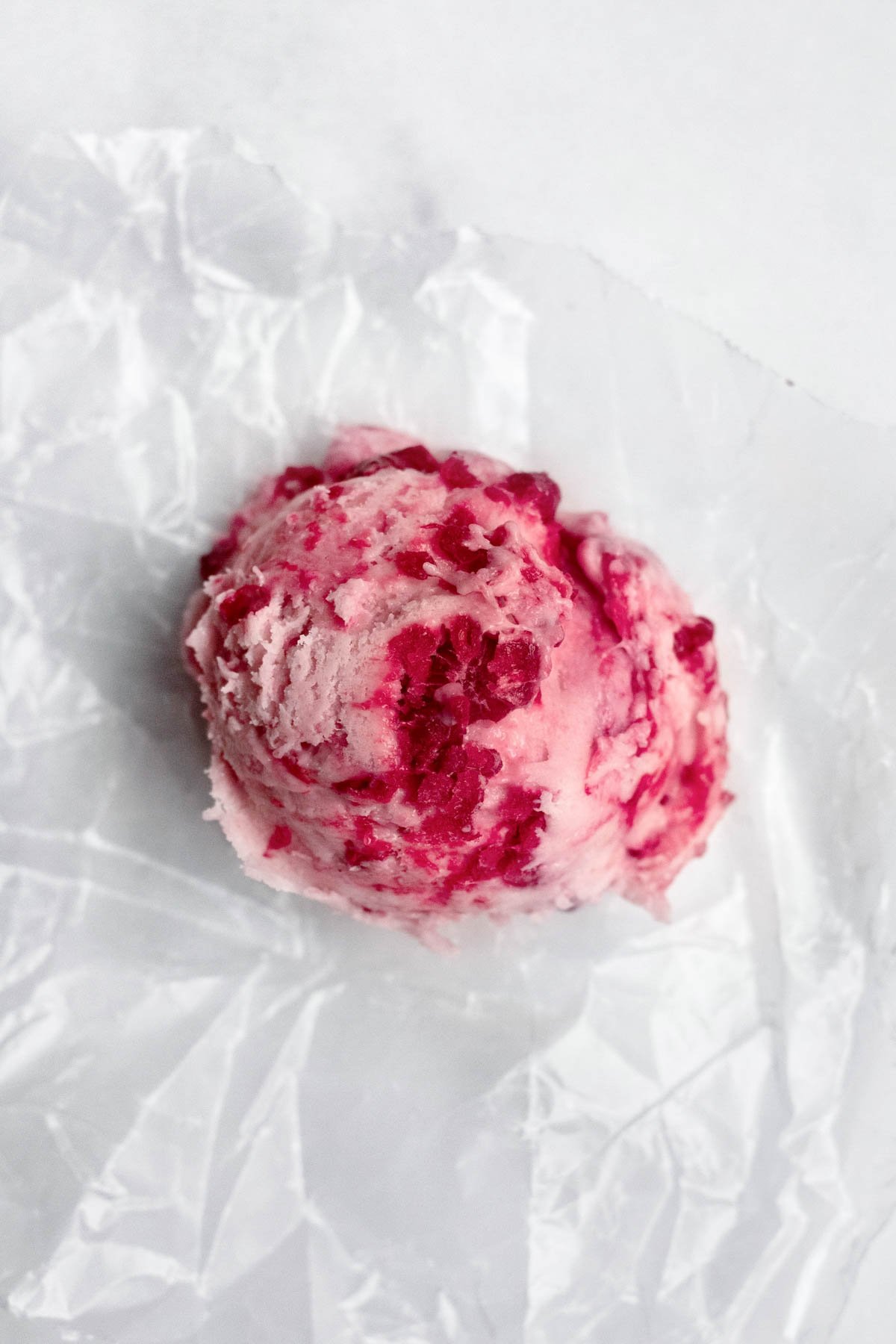 A scooped ball of raspberry infused cookie dough.
