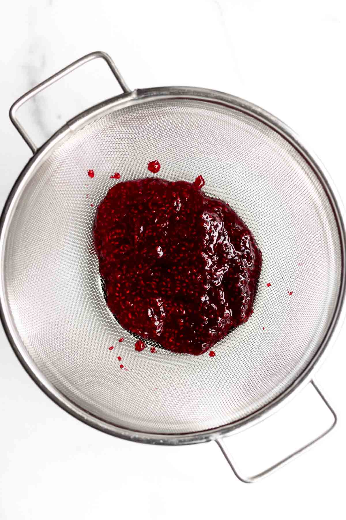A strainer with the raspberry sauce.