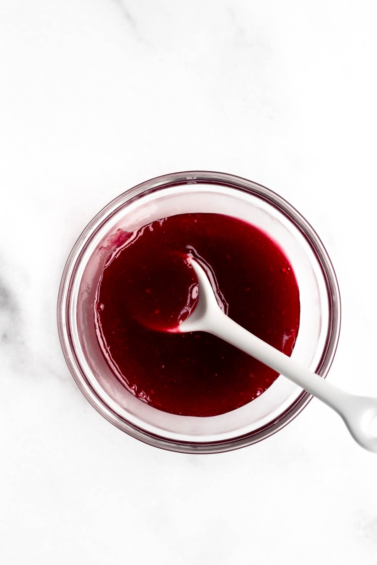 Bright red raspberry sauce without seeds in a glass bowl.