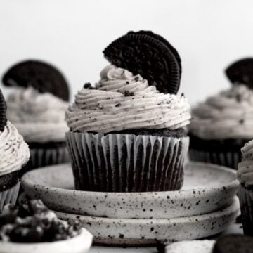 Cookies and Cream Cupcake topped with chocolate sandwich cookie infused vanilla frosting and half a cookie.